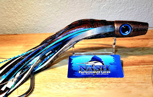 Fishing lure with a blue and black pattern on a wooden surface, branded 'Nash'.