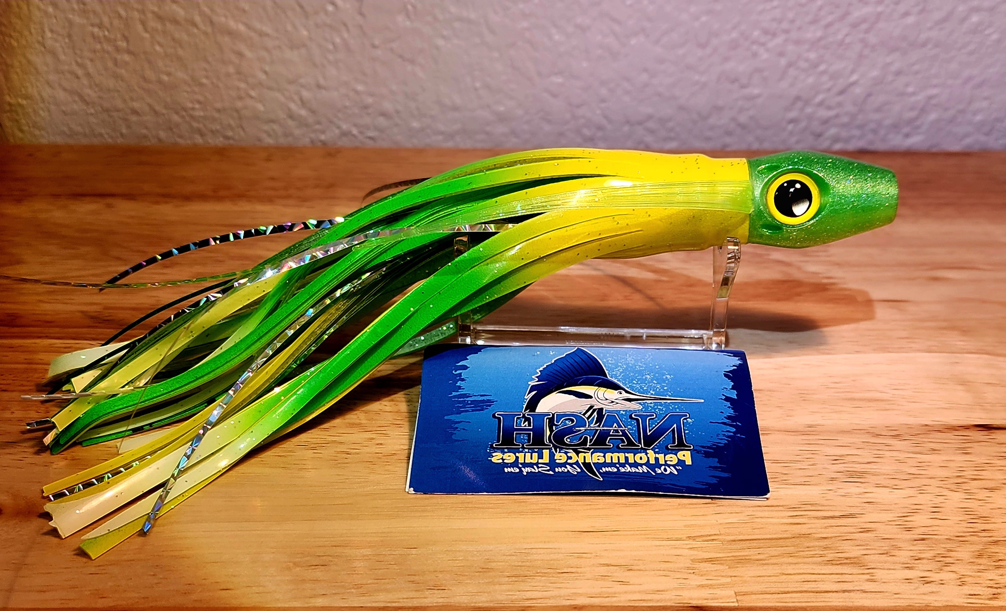 Green and yellow fishing lure on a wooden surface with a NASH Performance Lures packaging.